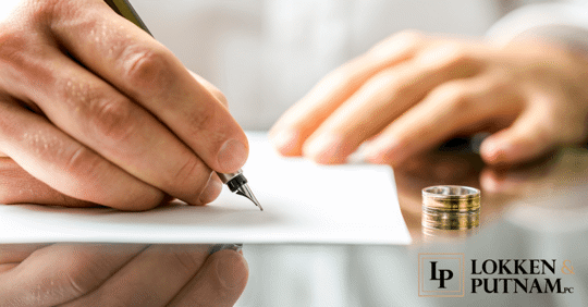 person signing paper with wedding ring next to them to symbolize the Utah divorce waiting period