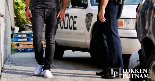 man walking in a line with police car and officer watching him