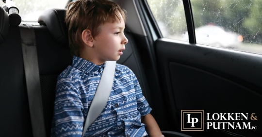 child in backseat of car looking out window