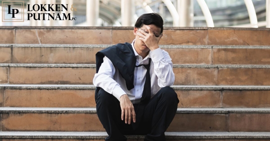 man with loose tie sitting on stairs with face in his hand and jacket on his shoulder